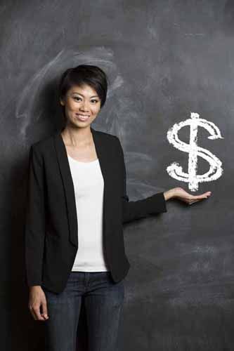 A woman stands in front of a chalkboard with a money sign drawn in chalk'